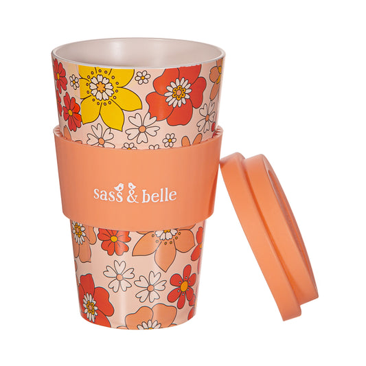 Orange 70's Floral Travel Cup with peach lid leaning against the cup and heat protector, with 'Sass & Belle' branding on a white background
