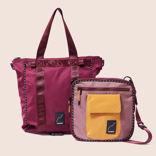 Two bags, one purple with a yellow pocket and the other maroon, on a beige background.