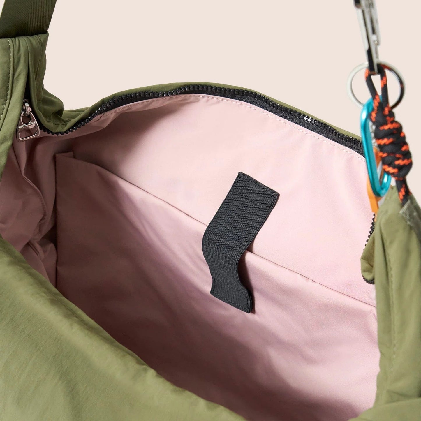 Gandys green bag with pink interior and black zipper pull on a beige background