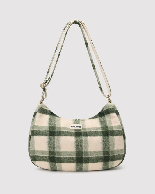 A soft, fuzzy crescent-shaped shoulder bag in a green and brown plaid pattern, featuring a matching plaid strap and a small 'hindbag' brand label on the front.