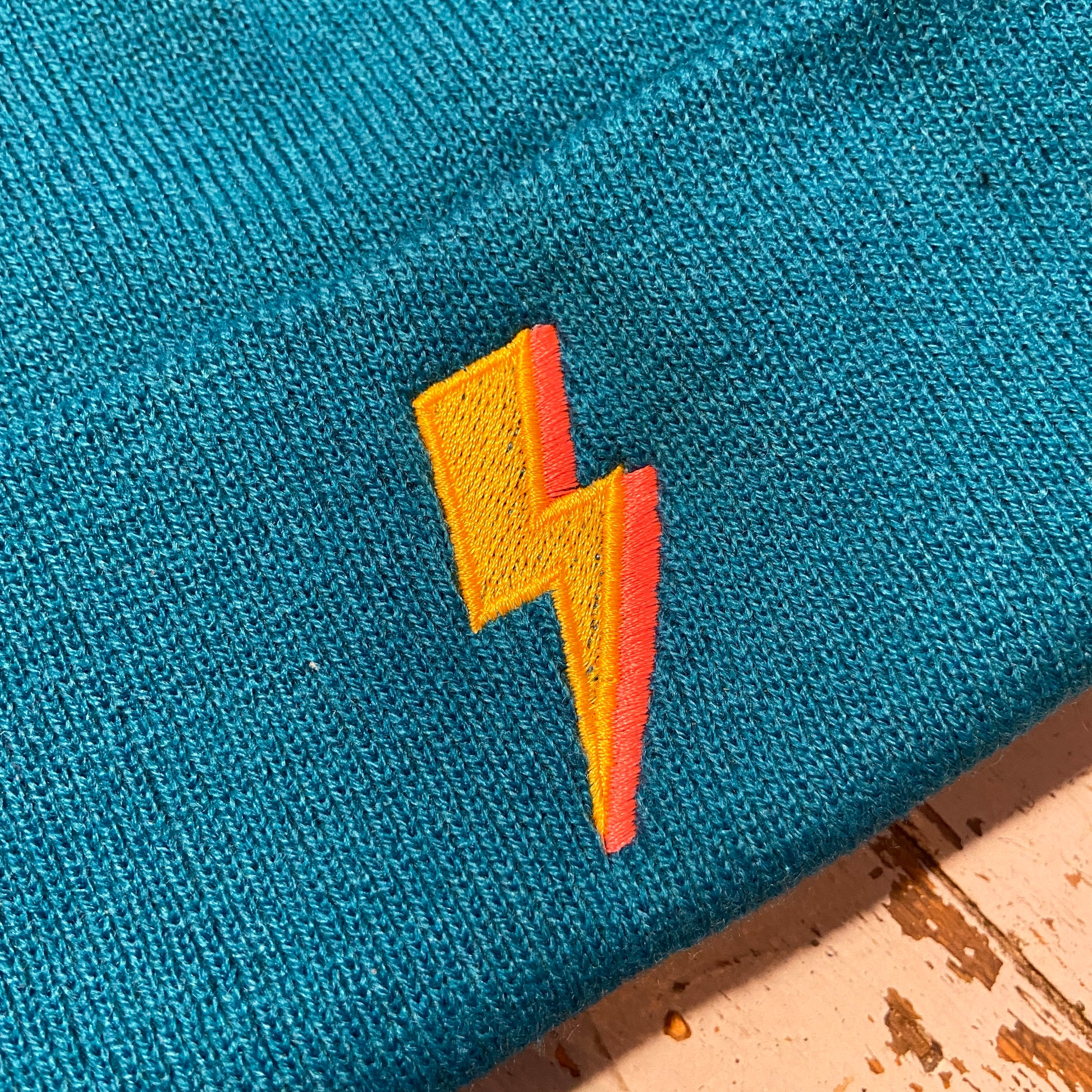 Embroidered to match our ever popular lighting bolt design.  Available in Teal or black  Beanies are made from 100% soft-touch acrylic in a double layer knit. One size fits all. Glitter & Mud