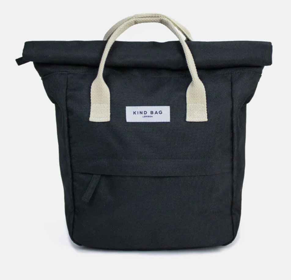 A black canvas tote bag with cream-colored webbed handles and a white brand label reading 'KIND BAG LONDON' on the front, set against a light gray background.