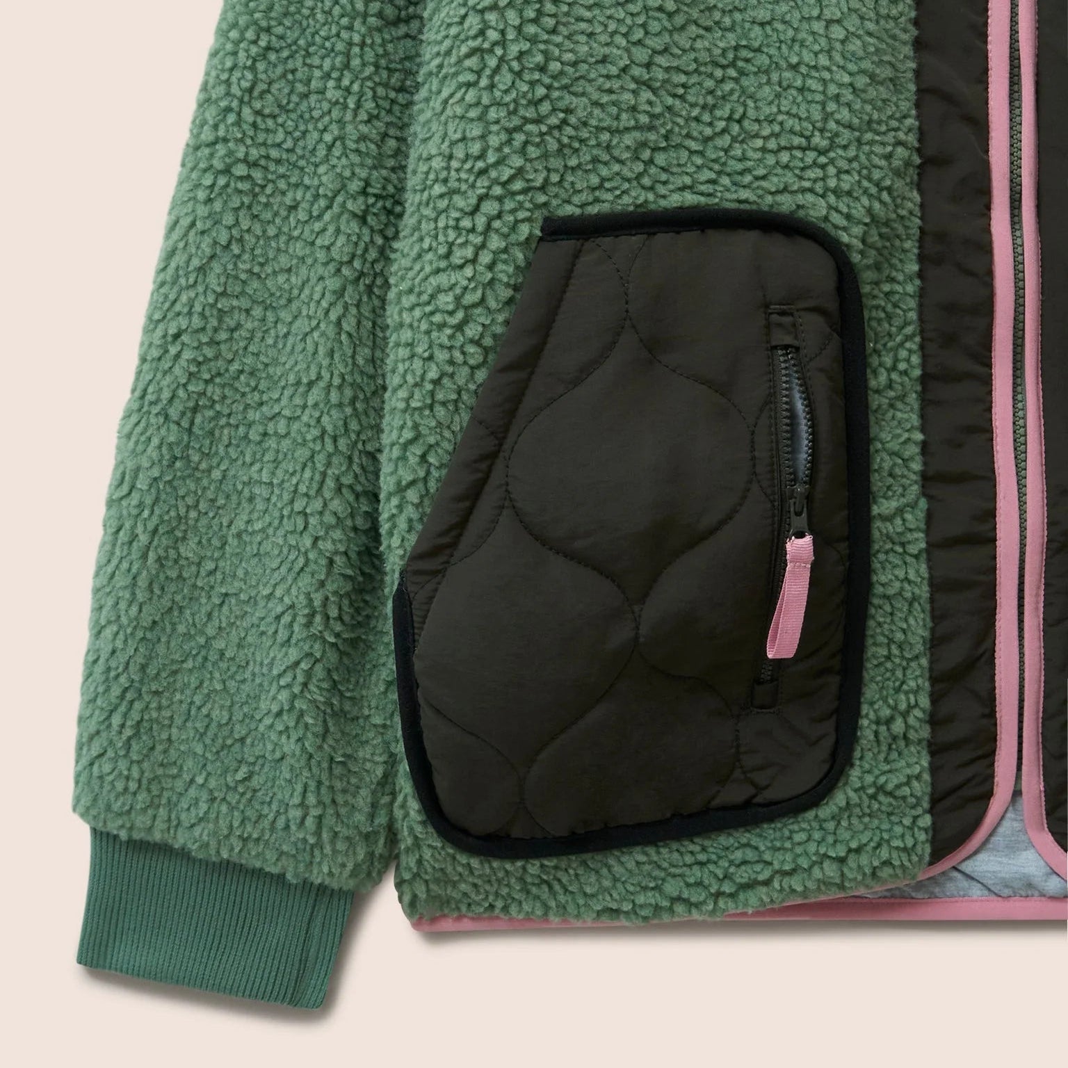 Gandys Green fleece jacket with a black pocket on a beige background