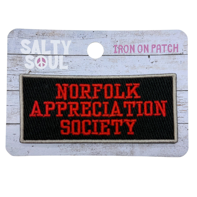 Embroidered Iron on patch with 'Norfolk Appreciation Society' text in red on black patch with a beige boarder on a wooden textured card with 'salty soul' branding 