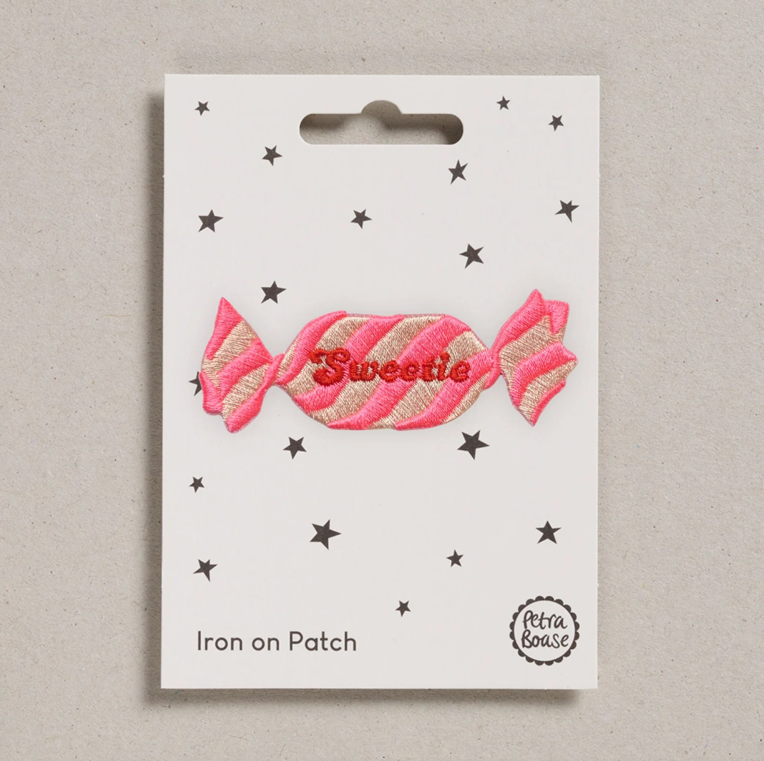 Embroidered iron on pink retro sweetie  patch, on a white card with black stars and 'Petra Boase' Branding 