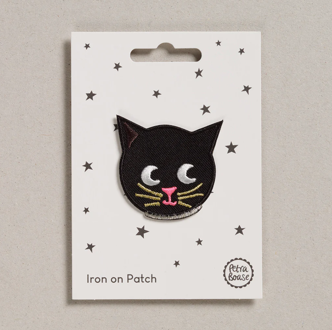 Embroidered iron on Black cat patch, on a white card with black stars and 'Petra Boase' Branding 