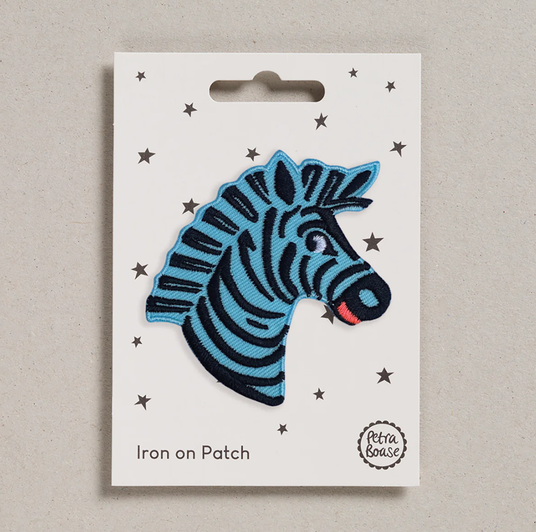 Embroidered iron on Blue Zebra head patch, on a white card with black stars and 'Petra Boase' Branding 