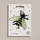 Embroidered iron on Gold Bee patch, on a white card with black stars and 'Petra Boase' Branding 