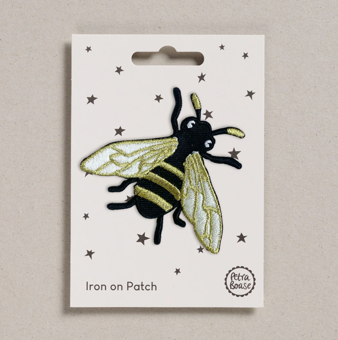 Embroidered iron on Gold Bee patch, on a white card with black stars and 'Petra Boase' Branding 