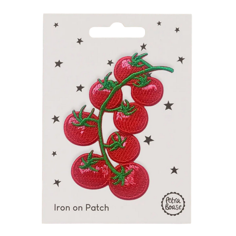 Embroidered Red tomato iron on patch with green stems on a white card with star patterns, branded 'Petra Boase'.