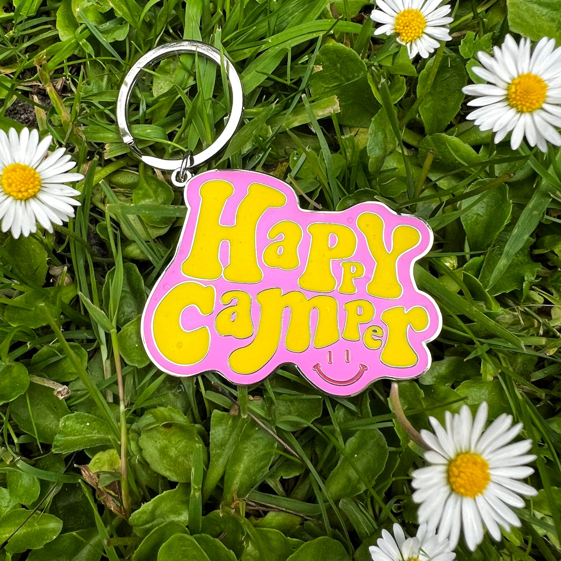 Happy camper pink and yellow enamel key ring on grass 