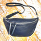 Navy XL leather bum bag with silver hardwear and detachable strap on a wooden surface 