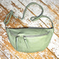 Pastel green XL leather bum bag with silver hardwear and detachable strap on a wooden surface 