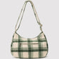 A green and cream plaid shoulder bag with a single shoulder strap and a front zippered pocket, shown against a light gray background.