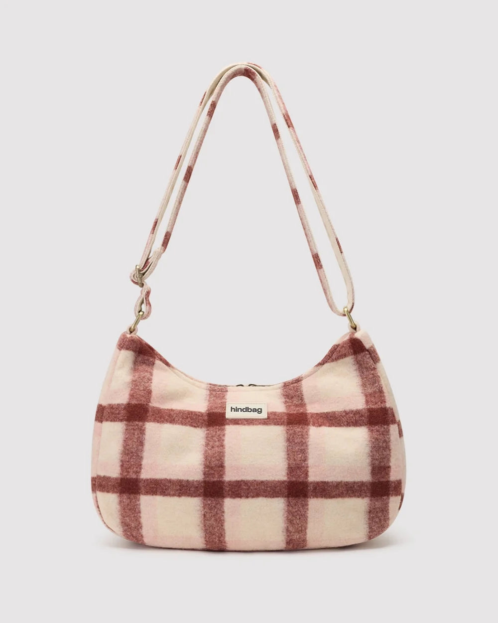 A soft, fuzzy crescent-shaped shoulder bag in a dusty pink and brown plaid pattern, featuring a matching plaid strap and a small 'hindbag' brand label on the front.