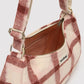 A close-up of a soft, fuzzy shoulder bag with a dusty pink and white plaid pattern, featuring a gold zipper and a small white 'handbag' brand label.