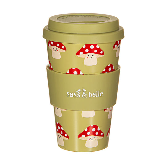 Smiling mushroom graphic green travel cup with green silicone heat protect and lid with 'Sass & Belle' branding on, on a white background 