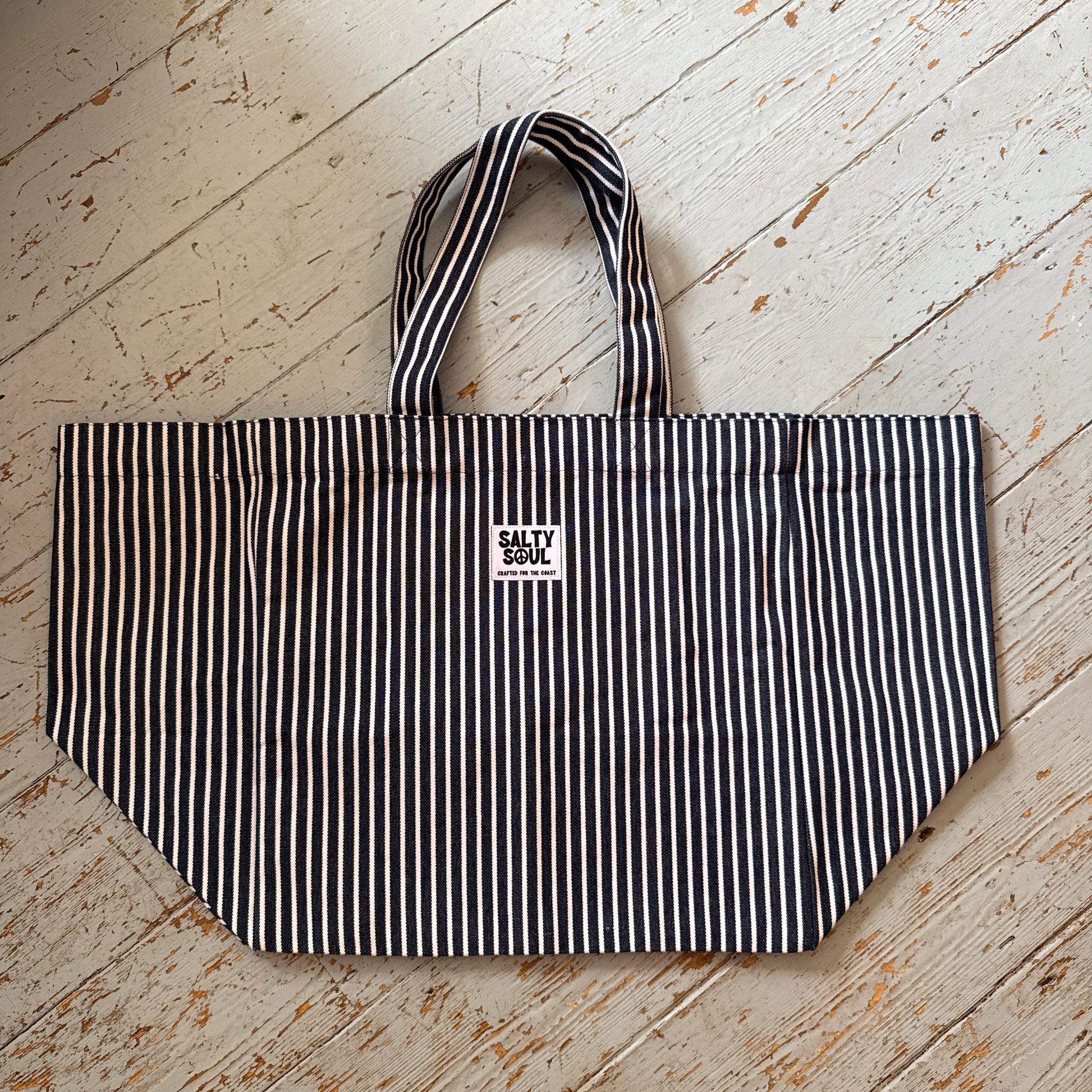 flat lay of striped salty soul tote on a wooden floor 