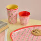 Two patterned cups and a matching tray on a yellow surface with a pink background.