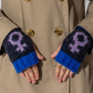 Person wearing blue and black knitted fingerless gloves with a lilac female symbol design, against a beige coat background.