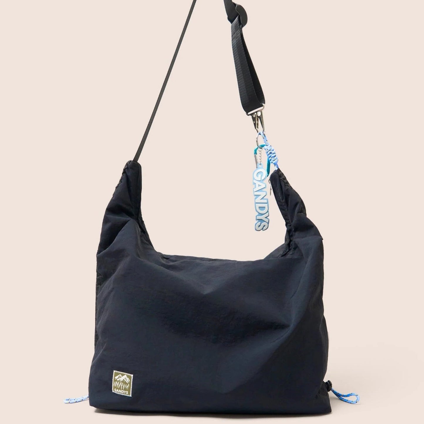 Gandys black shoulder bag with a strap on a beige background