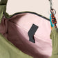 Gandys green bag with pink interior and black zipper pull on a beige background