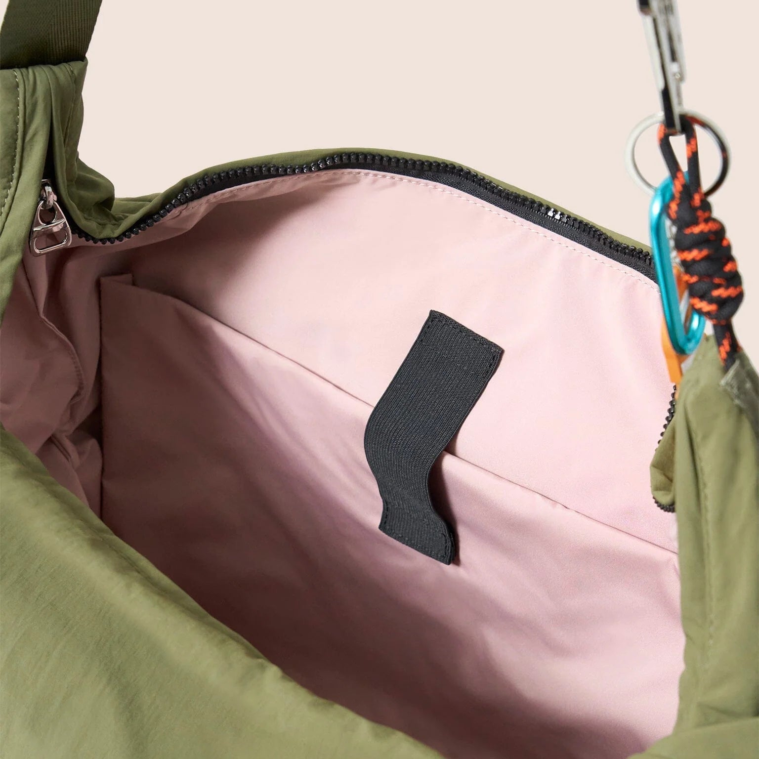 Gandys green bag with pink interior and black zipper pull on a beige background