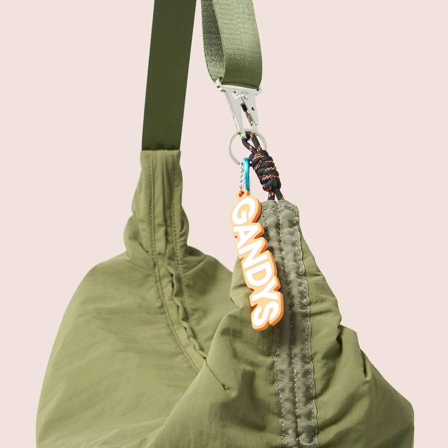 Gandys green bag with a strap and a visible brand tag on a beige background