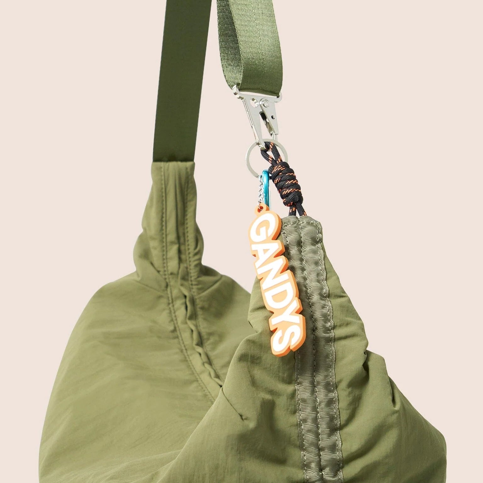 Gandys green bag with a strap and a visible brand tag on a beige background