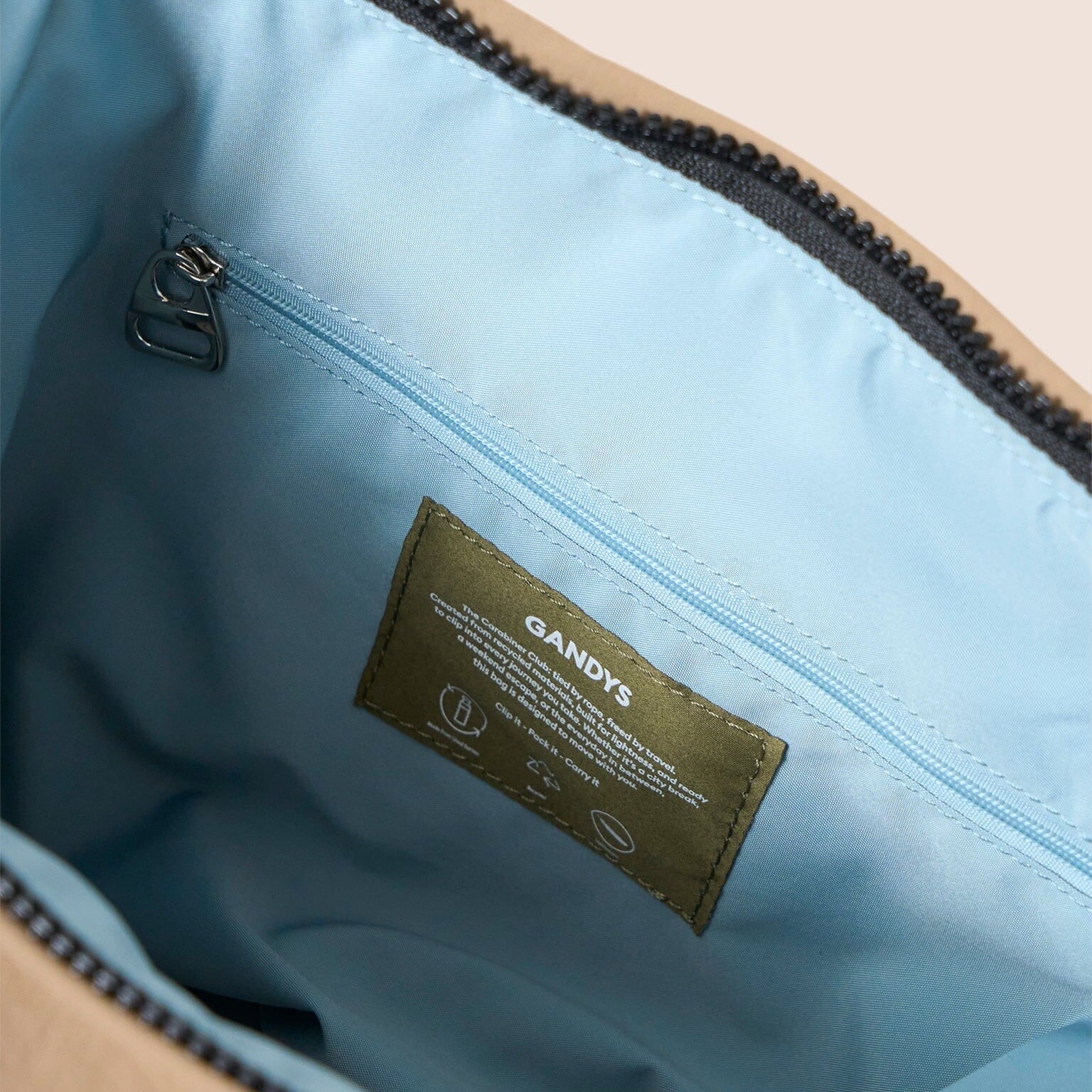 Close-up of a taupe bag with a blue interior and a visible brand label.