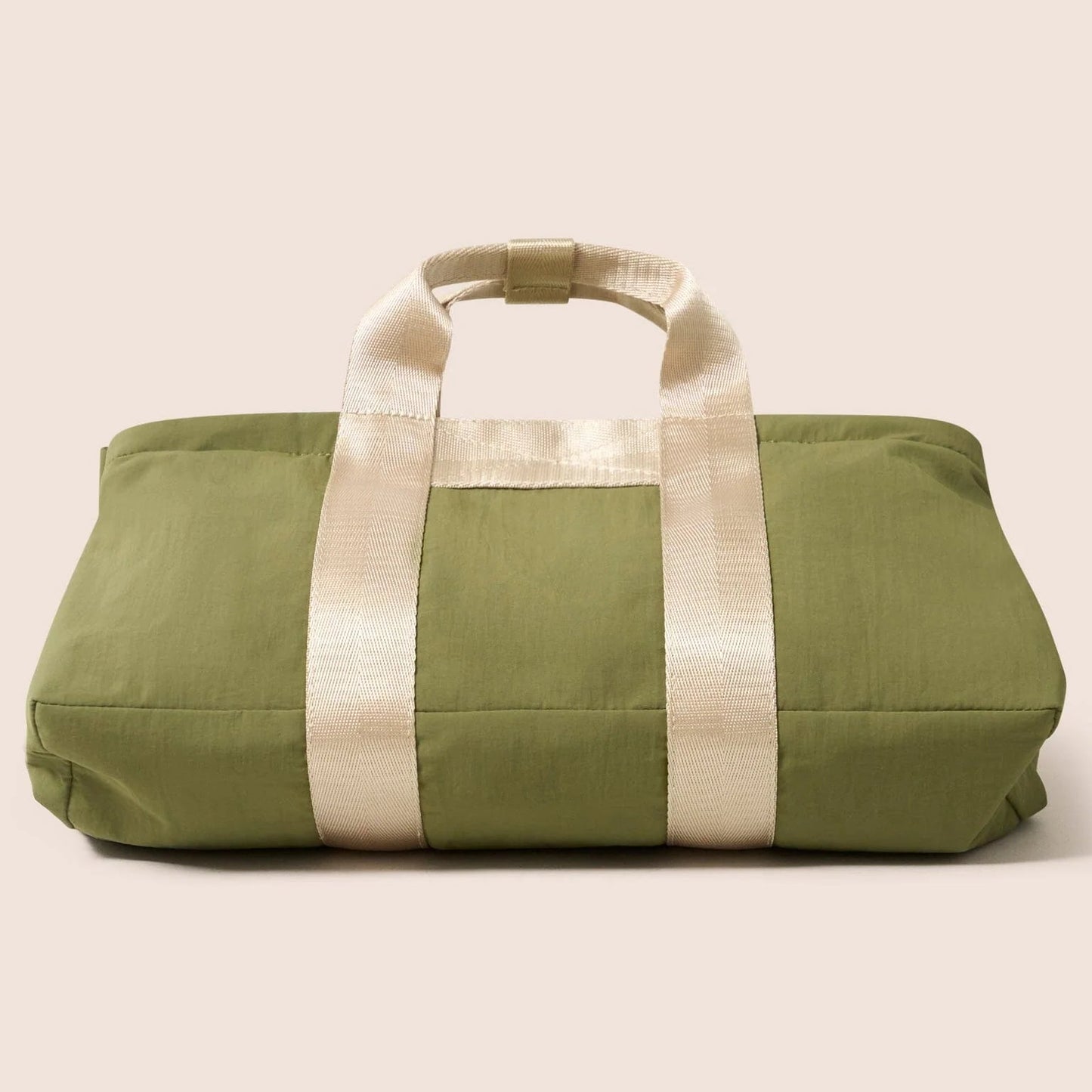 Green duffel bag with white straps on a beige background