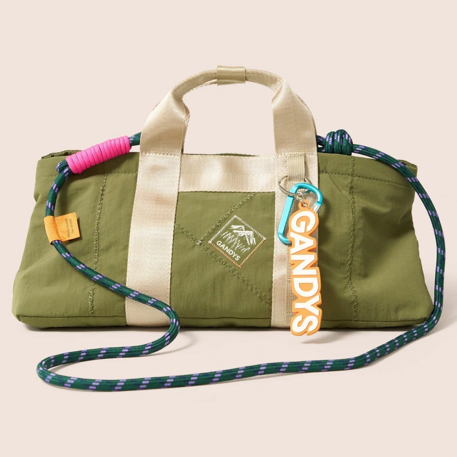 Gandys Green bag with a strap and colorful accents on a beige background