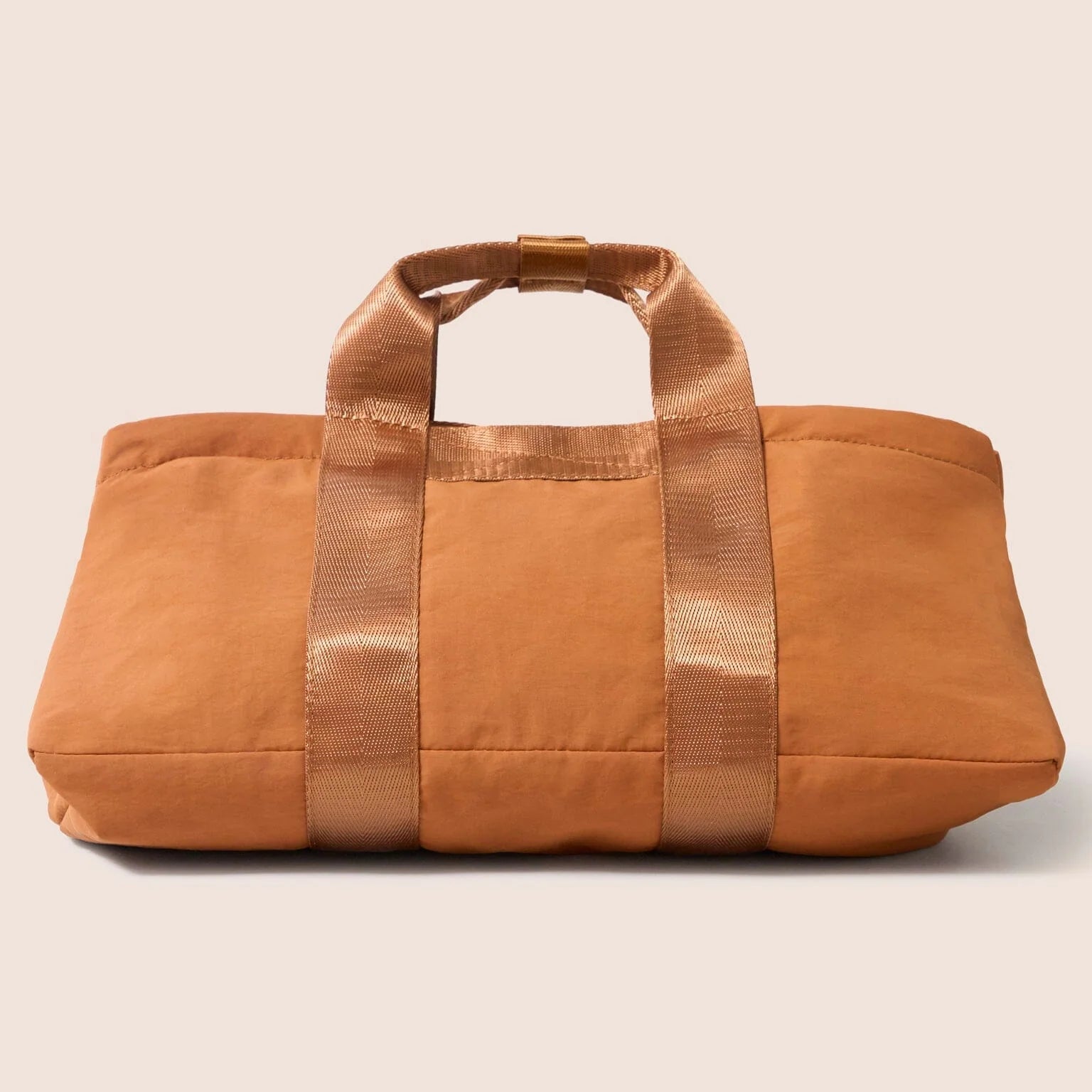 Gandys orange cube bag with a attached pouch on a beige background