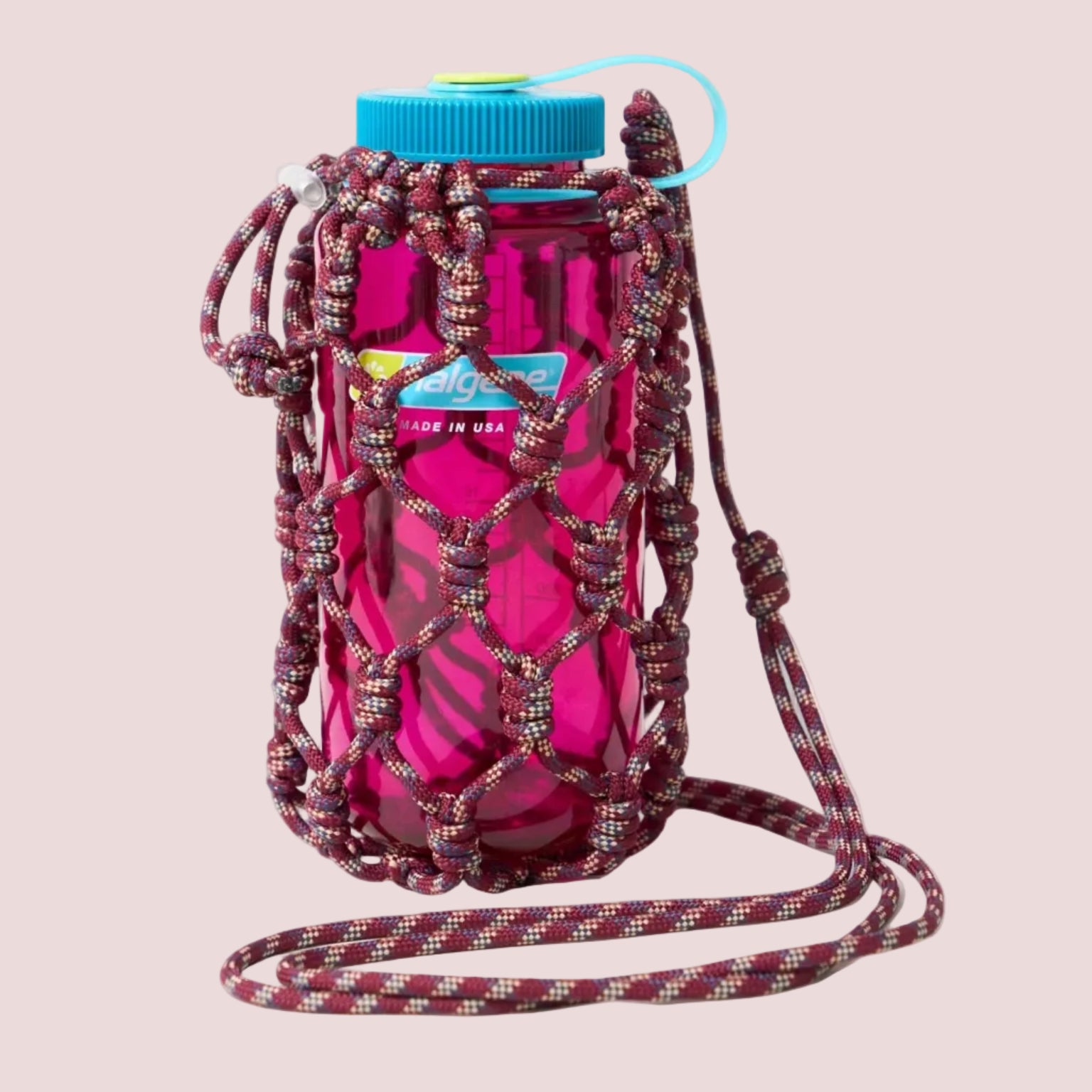 Pink water bottle with a beaded holder and blue cap on a beige background