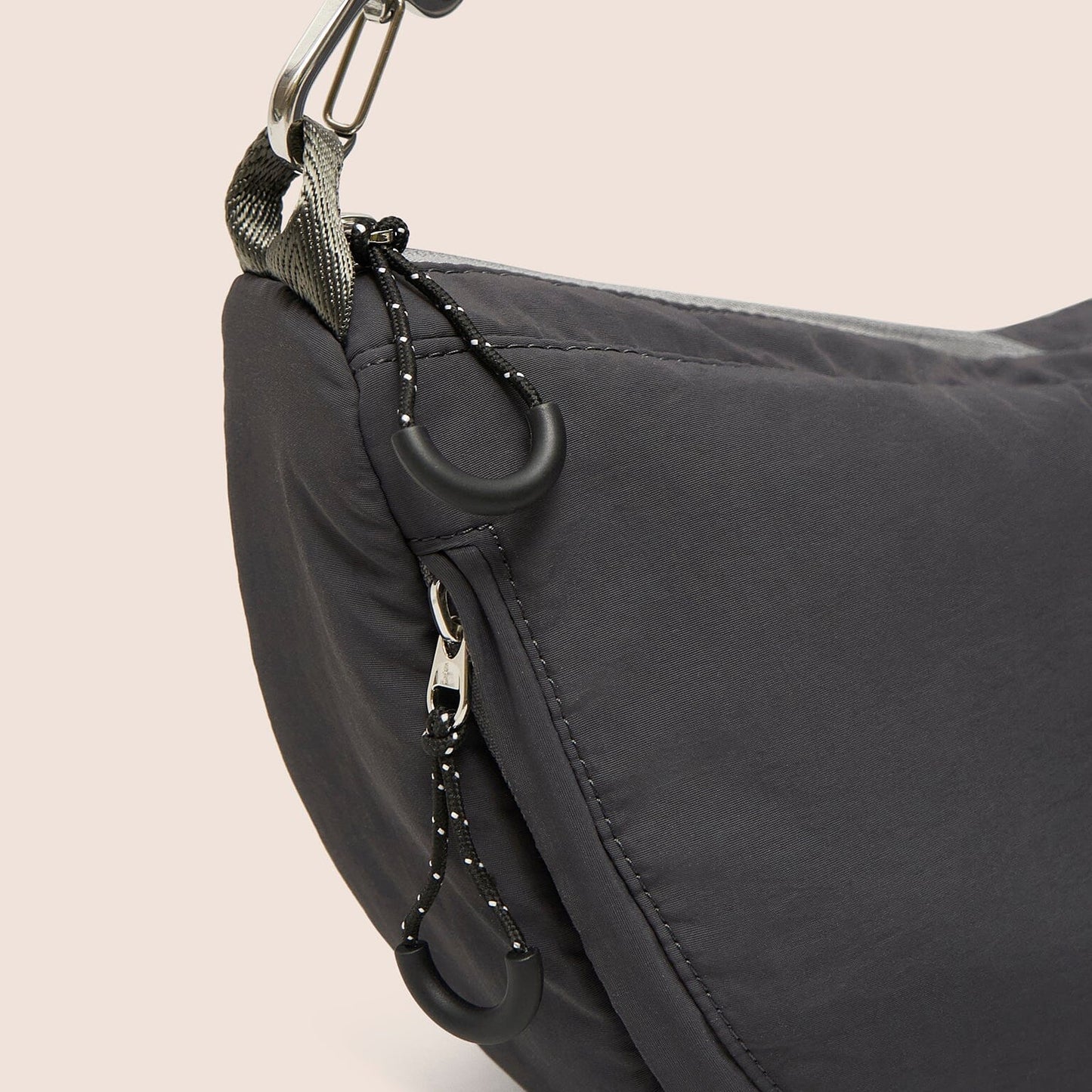 Gray shoulder bag with a keychain on a beige background