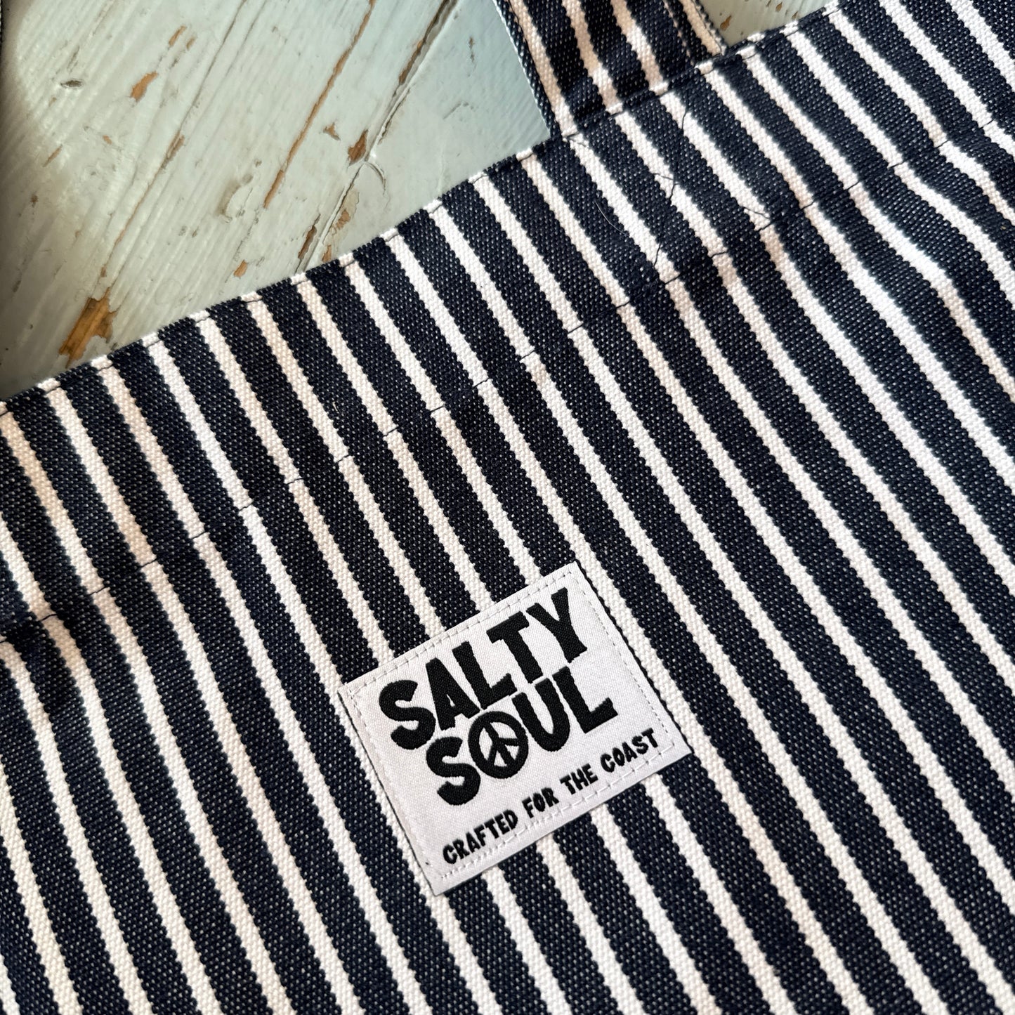 Close up of striped salty soul black and white striped tote bag label on a wooden floor 