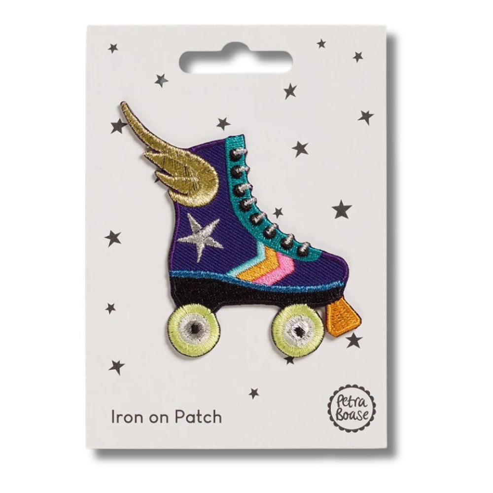Blue and colourful striped roller skate with gold wings iron on patch on a white card with black stars and 'petra boase' branding on a white background.