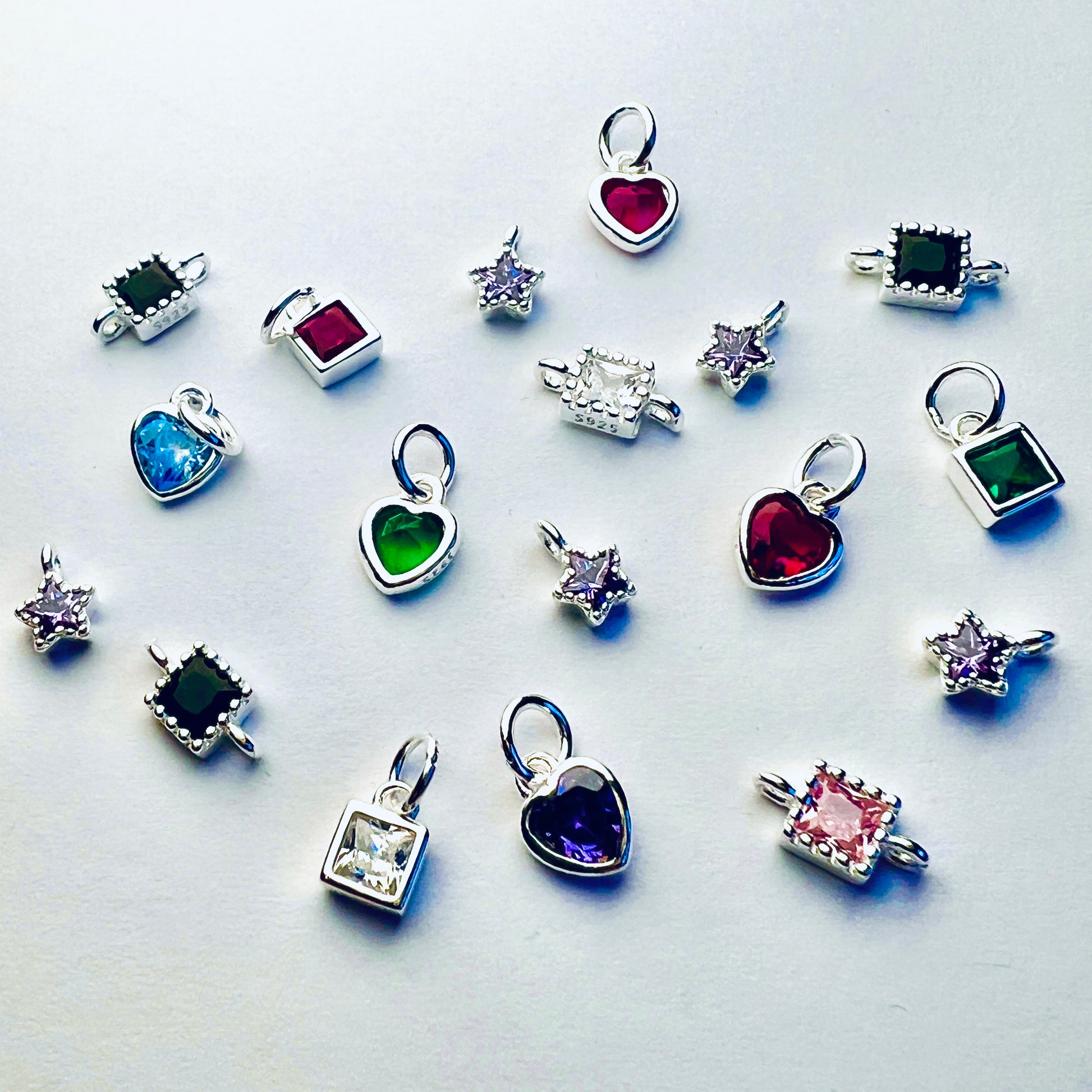 Colourful stone silver charms for jewellery laying out on a white background