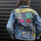 Denim jacket with colourful Petra boase patches and embroidery on a person against a black background