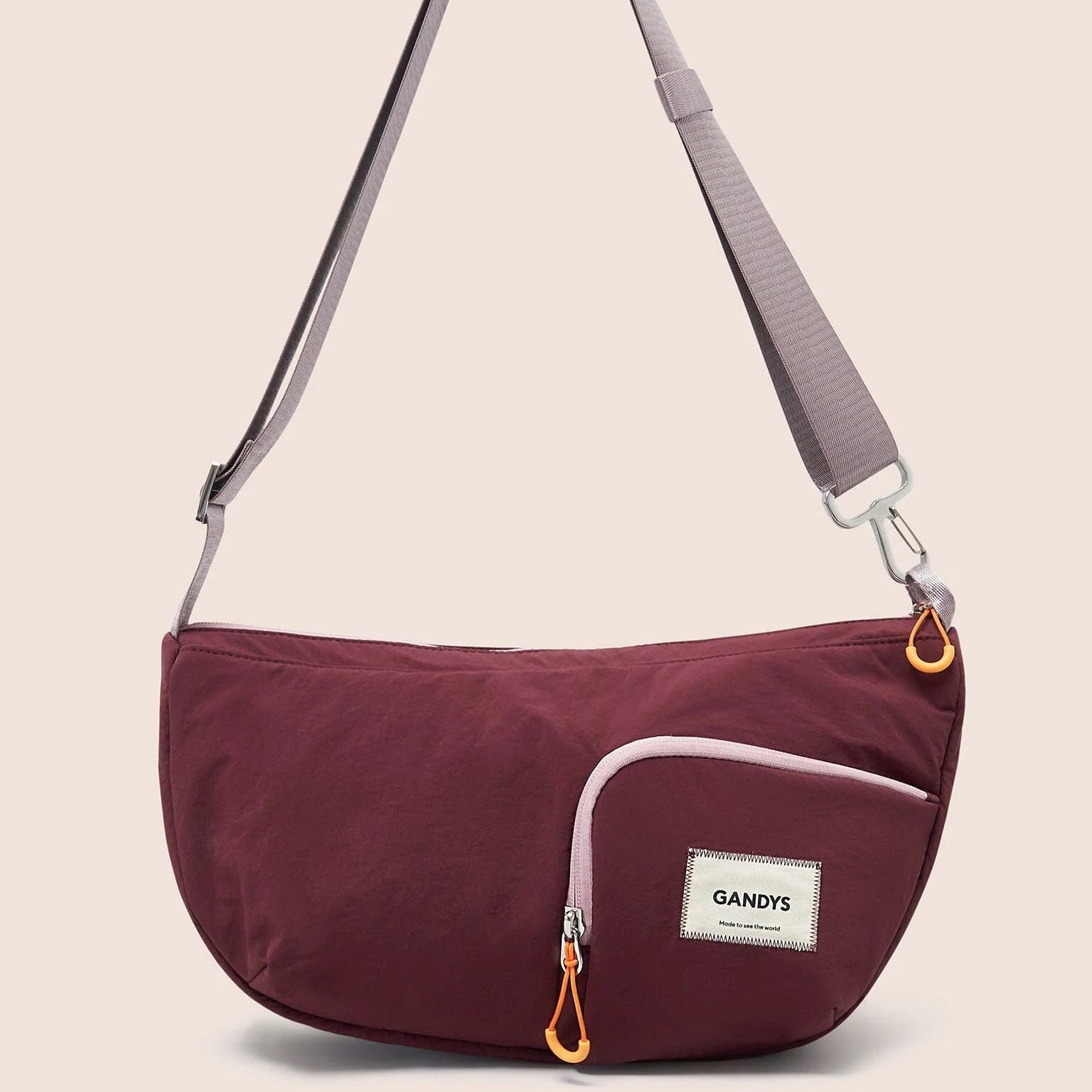 Gandys sling shoulder bag with a visible brand label on a beige background