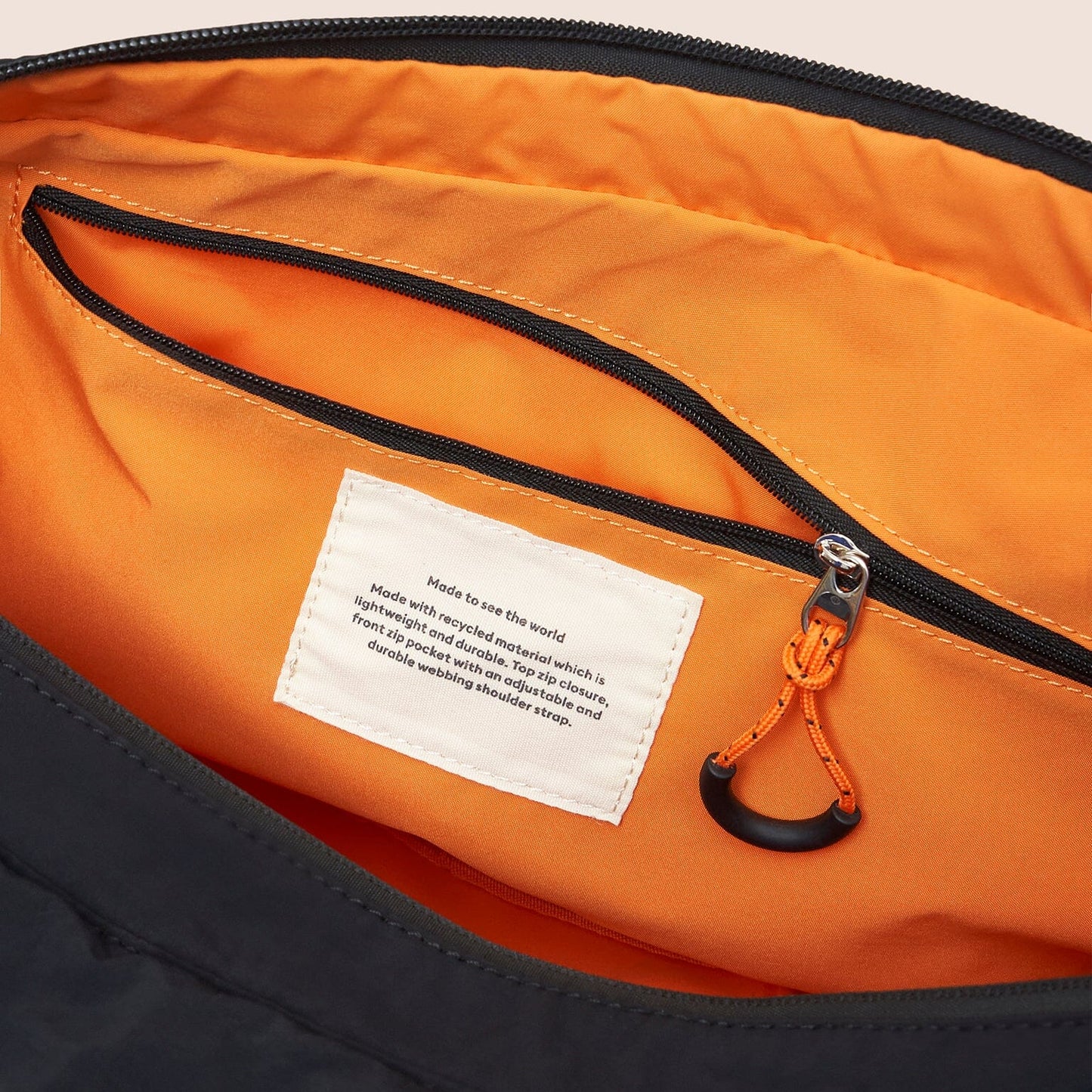 Close-up of a black and orange bag with a label inside