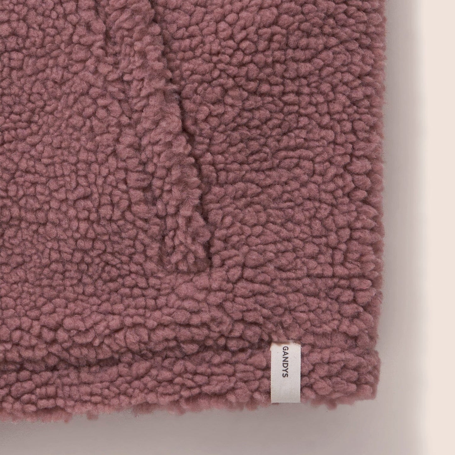 Close-up of a pink textured fabric with a brand label on a light background