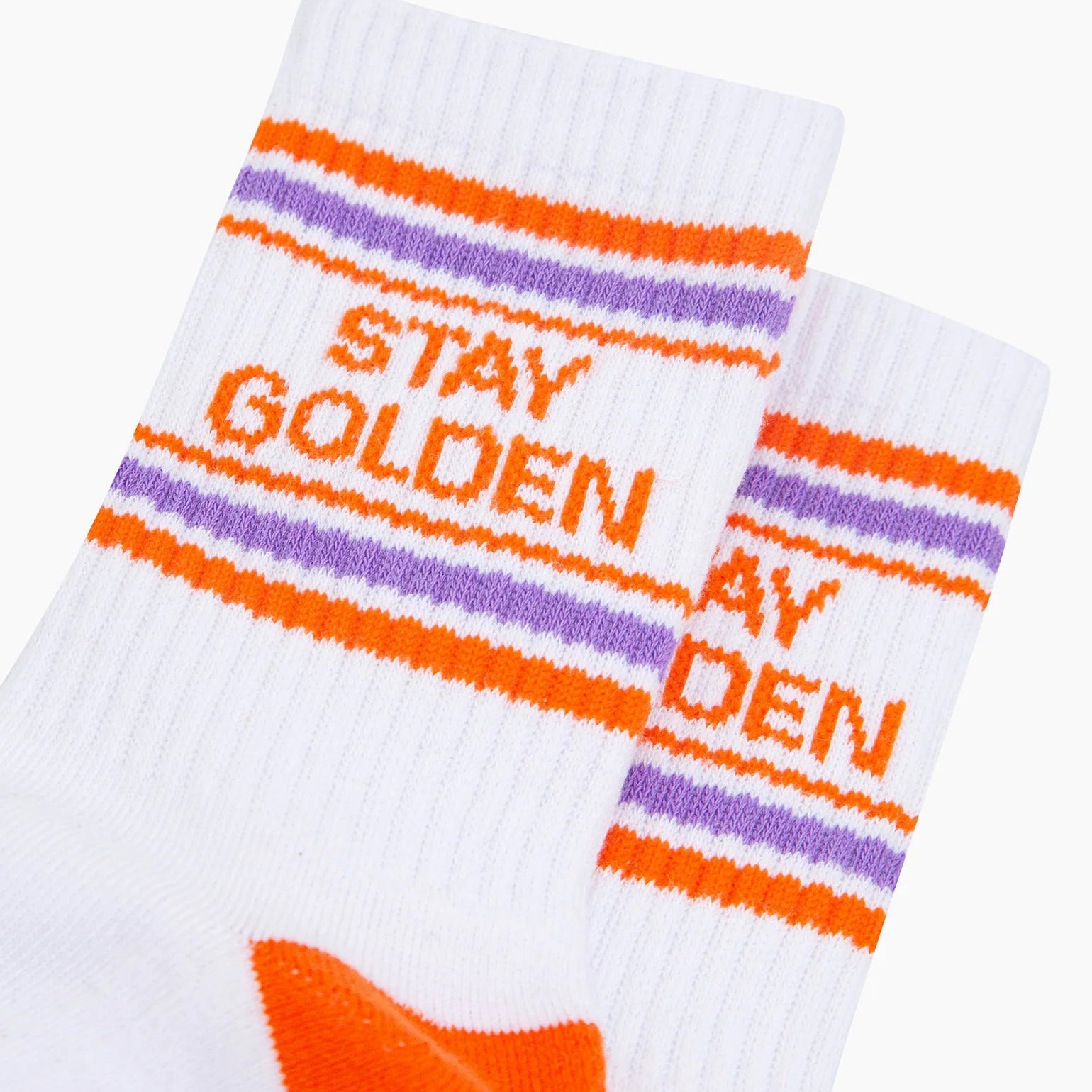 White socks with orange and purple stripes and harry styles 'Stay Golden' text on a white background