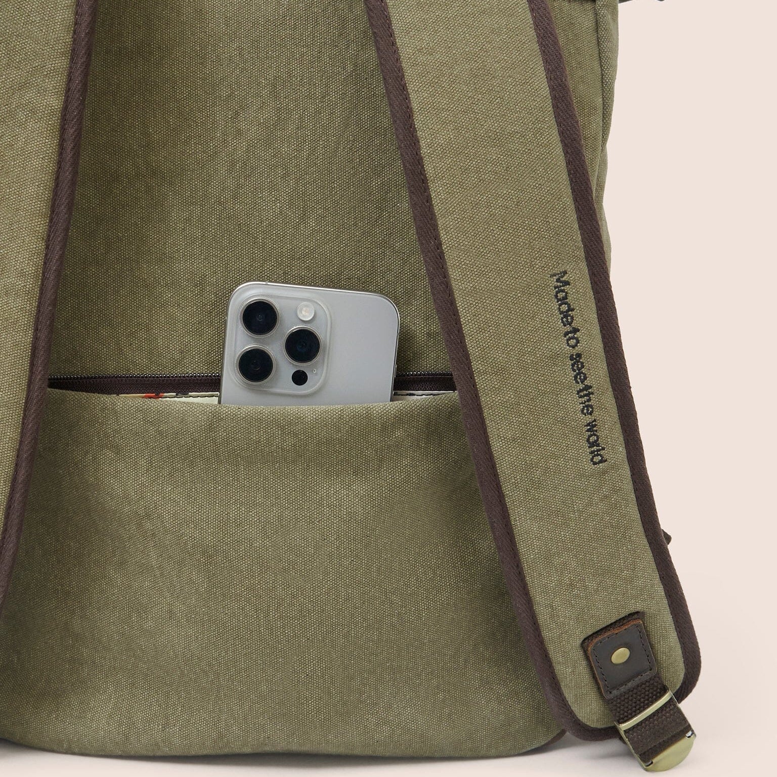 Gandys green backpack with a pocket containing a smartphone on a beige background