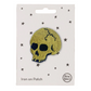 A metallic gold skull patch with iron-on backing, displayed on a card with small stars around it Petra Boase branding