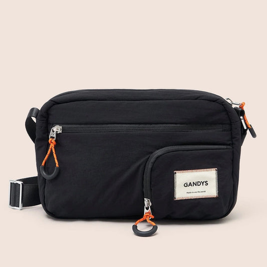 Black waist bag with orange zippers and 'GANDYS' brand label on a beige background
