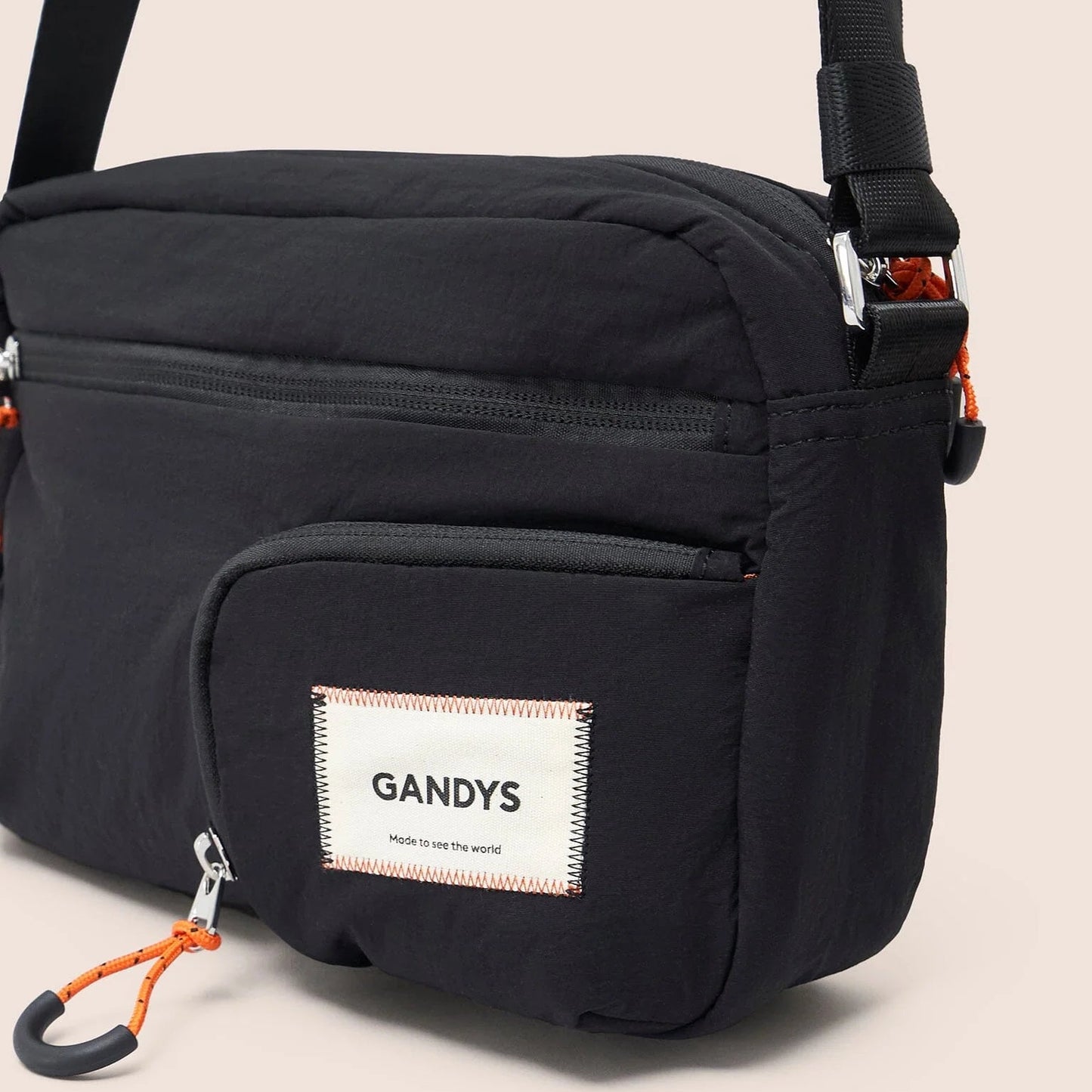 Black shoulder bag with a visible 'GANDYS' label on a beige background