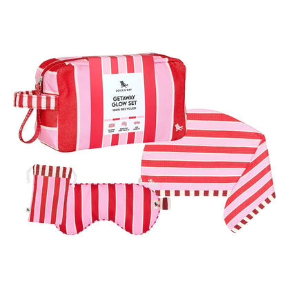 Pink and red striped Dock & Bay Getaway Glow Set containing a zippered pouch, a face mask, and a towel, displayed on a clean white background.