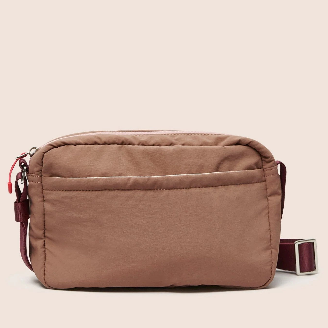 Gandys pink crossbody bag with pink accents on a beige background