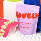 Purple packaging of 'Lovely' rose and coconut bath salts on a grid background